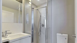 Une salle de bain moderne avec une douche à parois de verre, un lavabo blanc et des toilettes.