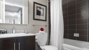 Ein modernes Badezimmer mit Toilette, Badewanne und großem Spiegel über dem Waschbecken.