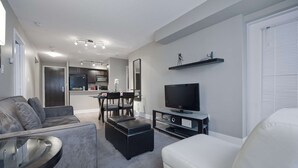Ein modernes Wohnzimmer mit Sofa, Hocker und Fernsehschrank.