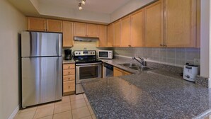 A kitchen with wooden cabinets, stainless steel appliances, granite countertops, and a built-in oven. - 2 Bedroom/2 Bathroom Suite (Scarborough ON)