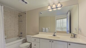 A bathroom with a bathtub, toilet, sink, and a large mirror. - 2 Bedroom/2 Bathroom Suite (Scarborough ON)