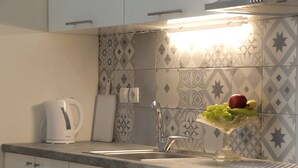 A kitchen with a modern design, featuring a sink, a kettle, and a fruit bowl on the counter. - Stylish Modern Apartment (Thessaloniki)