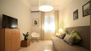 A living room with a sofa, television, and a potted plant. - Stylish Modern Apartment (Thessaloniki)