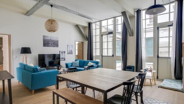 A modern living room with a large wooden table, blue sofas, and a TV. - PHILIPPE AUGUSTE LOFT 2 - Loft for 10 - 4 rooms - BASTILLE - PÈRE LACHAISE (Paris)
