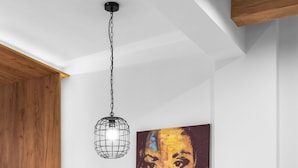 A dining area with a round table, four chairs, a pendant light, and a large painting on the wall. - White and Wood Nilie Hospitality MGMT (Thessaloniki)