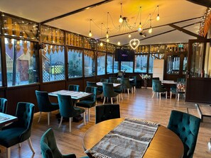 Un restaurant avec des chaises de couleur turquoise, des tables en bois et un lustre.
