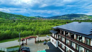 A hotel with a solar panel roof, a parking area, and a view of a green valley.