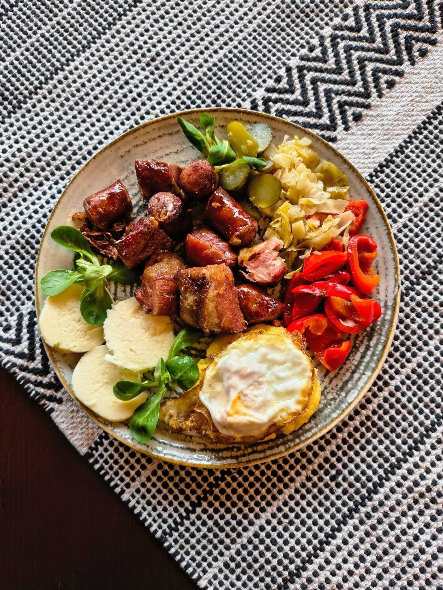 Un plato de comida con salchichas, pimientos rojos y un huevo frito.