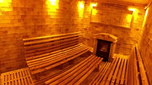 A sauna with wooden benches and a stone wall.