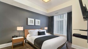 Ein modernes Hotelzimmer mit einem Bett, Nachttischen, einem Fernseher und einem Fenster mit Vorhängen.