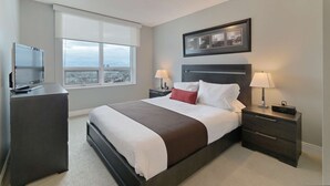 A hotel room with a large bed, a TV, a desk, and a window with a city view. - 2 Bedroom/2 Bathroom Suite (Etobicoke)