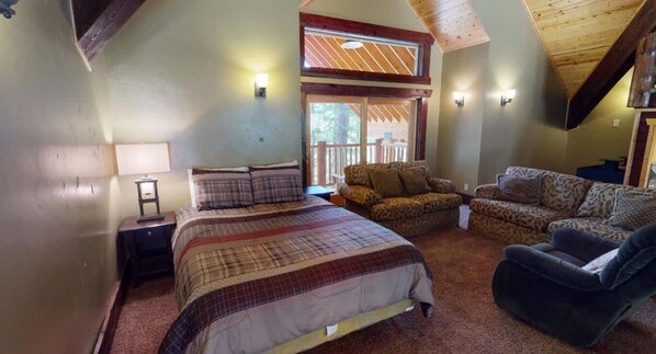 A bedroom with a bed, two sofas, a nightstand, and a window.