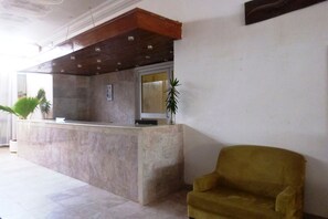 A reception area with a marble counter, a wooden ceiling, and a yellow armchair. - Fajara Resort (Serrekunda)