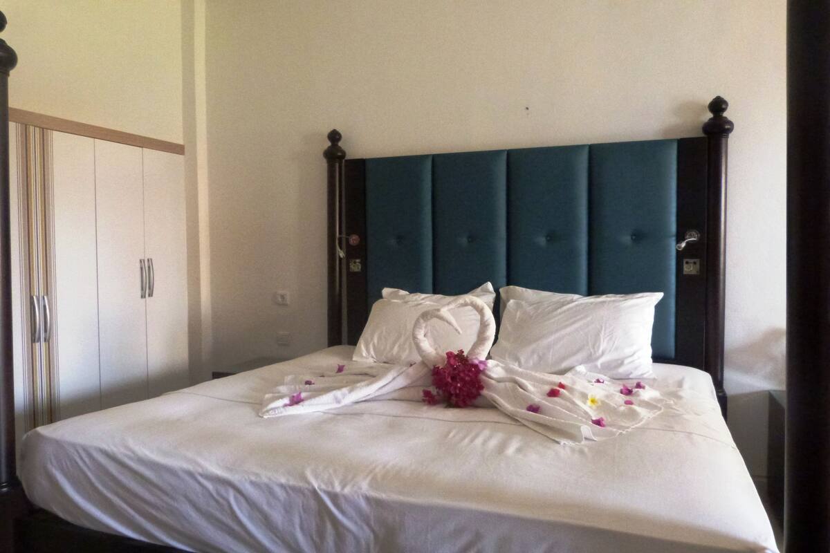 A neatly made bed with white linens and a decorative pillow arrangement.