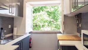 A modern kitchen with a large window, a built-in microwave, and a wooden countertop. - Bairro Conqvistador Apartment 4 (Lisboa)