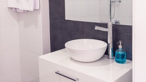 A modern bathroom with a white sink, a large mirror, and a glass shower enclosure. - Bairro Conqvistador Apartment 4 (Lisboa)