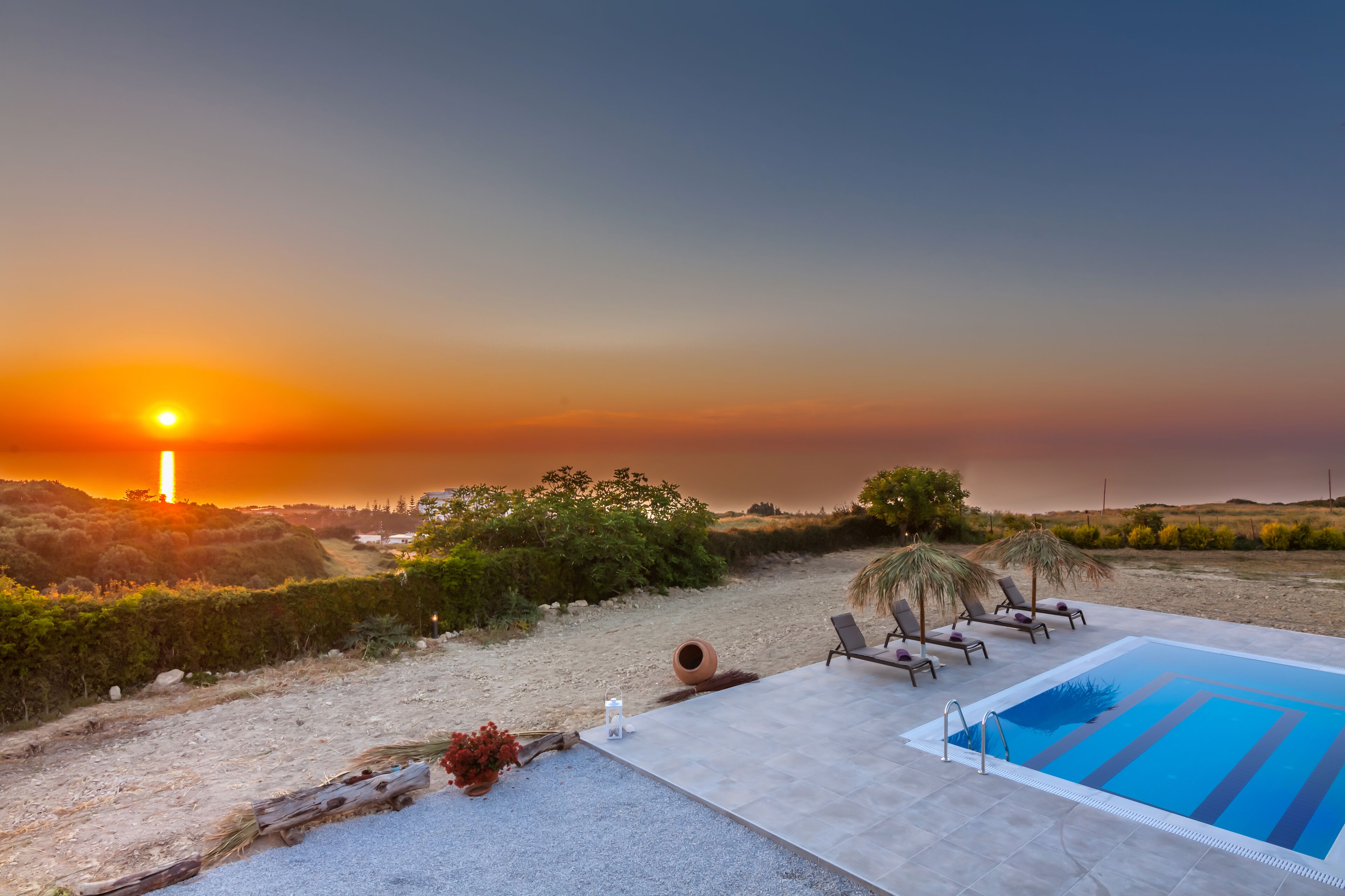 Ein Poolbereich mit Liegestühlen und Blick auf den Sonnenuntergang.