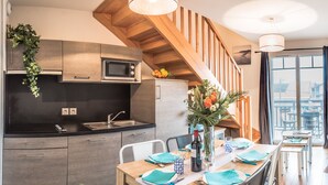 A modern kitchen with a microwave, sink, and wooden staircase.