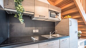 A modern kitchen with a black countertop, stainless steel appliances, and wooden cabinets.