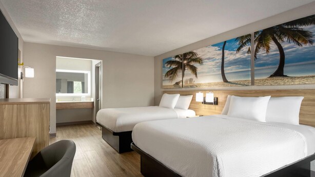 A hotel room with two beds, a desk, and a TV. - Days Inn by Wyndham Apopka/Orlando (Apopka)