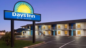 A Days Inn by Wyndham with a large sign, a parking lot, and a building with multiple floors and balconies. - Days Inn by Wyndham Apopka/Orlando (Apopka)