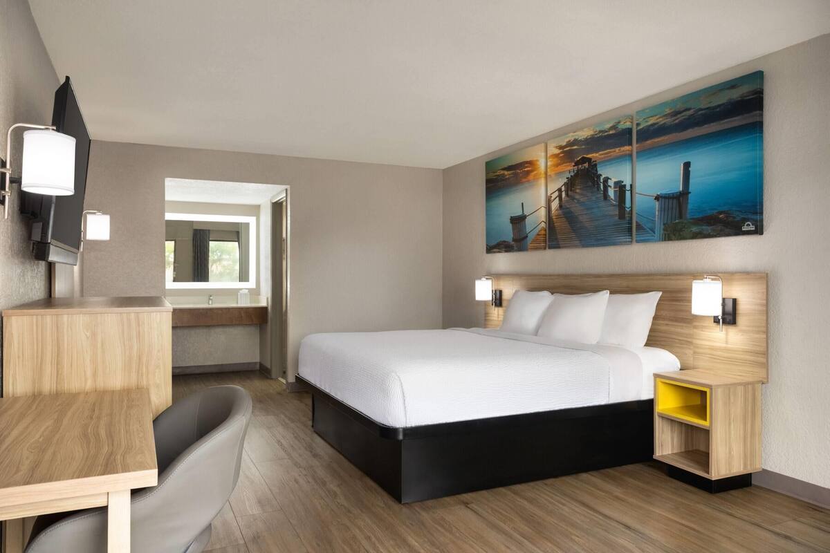 A hotel room with a bed, bedside tables, a desk, and a chair.