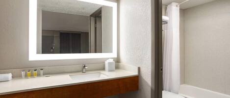 Un baño con lavamanos, espejo e inodoro blancos.