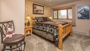 A cozy room with a wooden bed, a chair, a lamp, and a wall painting.