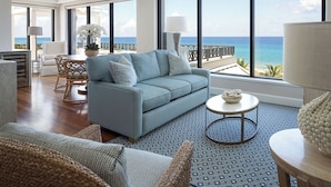 A spacious living room with a large window offering a view of the ocean, a comfortable sofa, a dining area, and a decorative lamp. - Opal Grand Oceanfront Resort & Spa (Delray Beach)