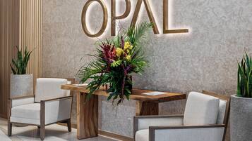 Zona de recepción con diseño moderno, que incluye un mostrador de recepción, dos sillas y un cartel grande montado en la pared con el texto "OPAL".