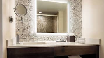 A modern bathroom with a large mirror, two sinks, and a dark wood vanity.
