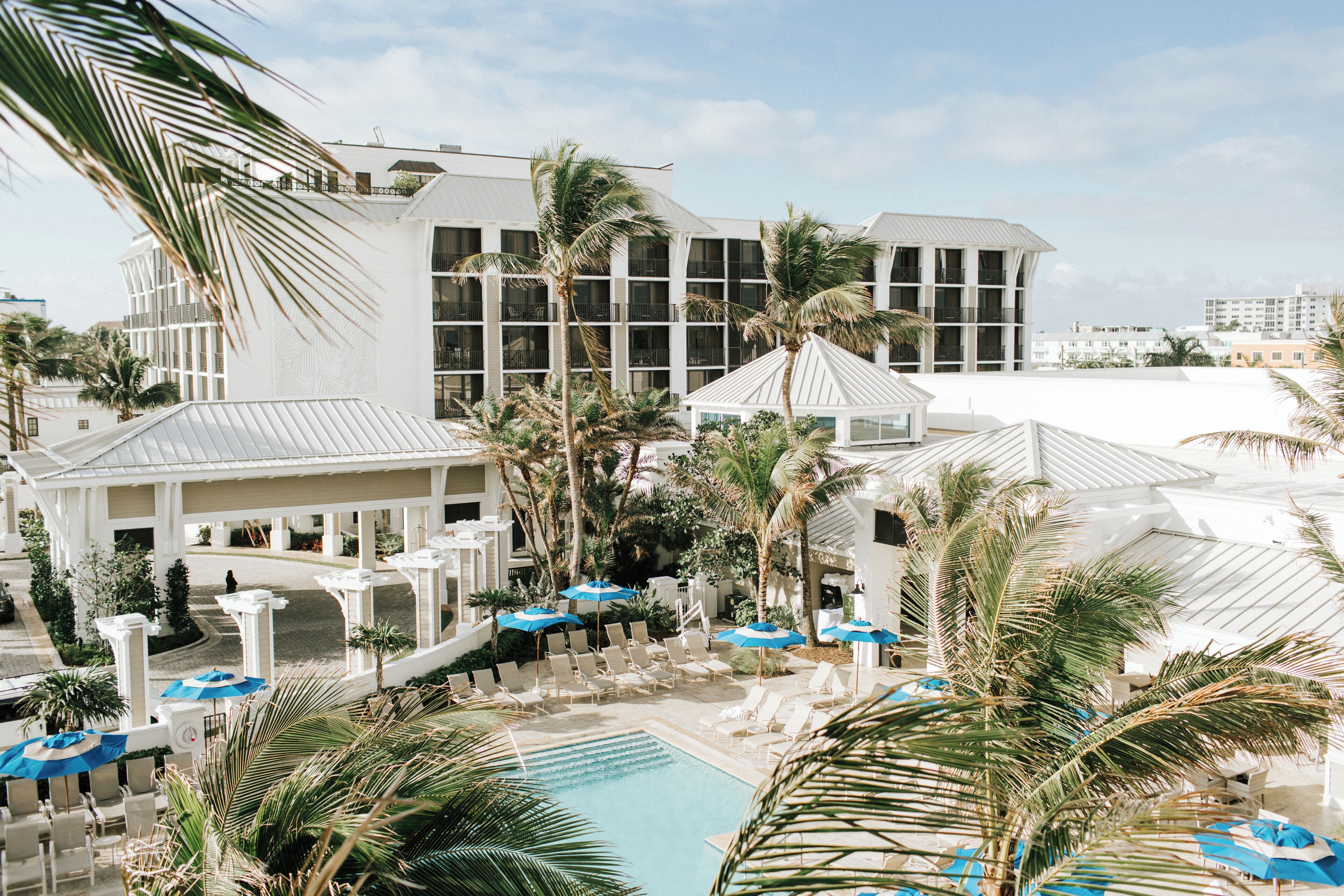 A resort with a pool area, lounge chairs, and palm trees.