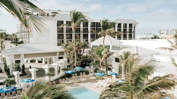 A resort with a pool area, lounge chairs, and palm trees.