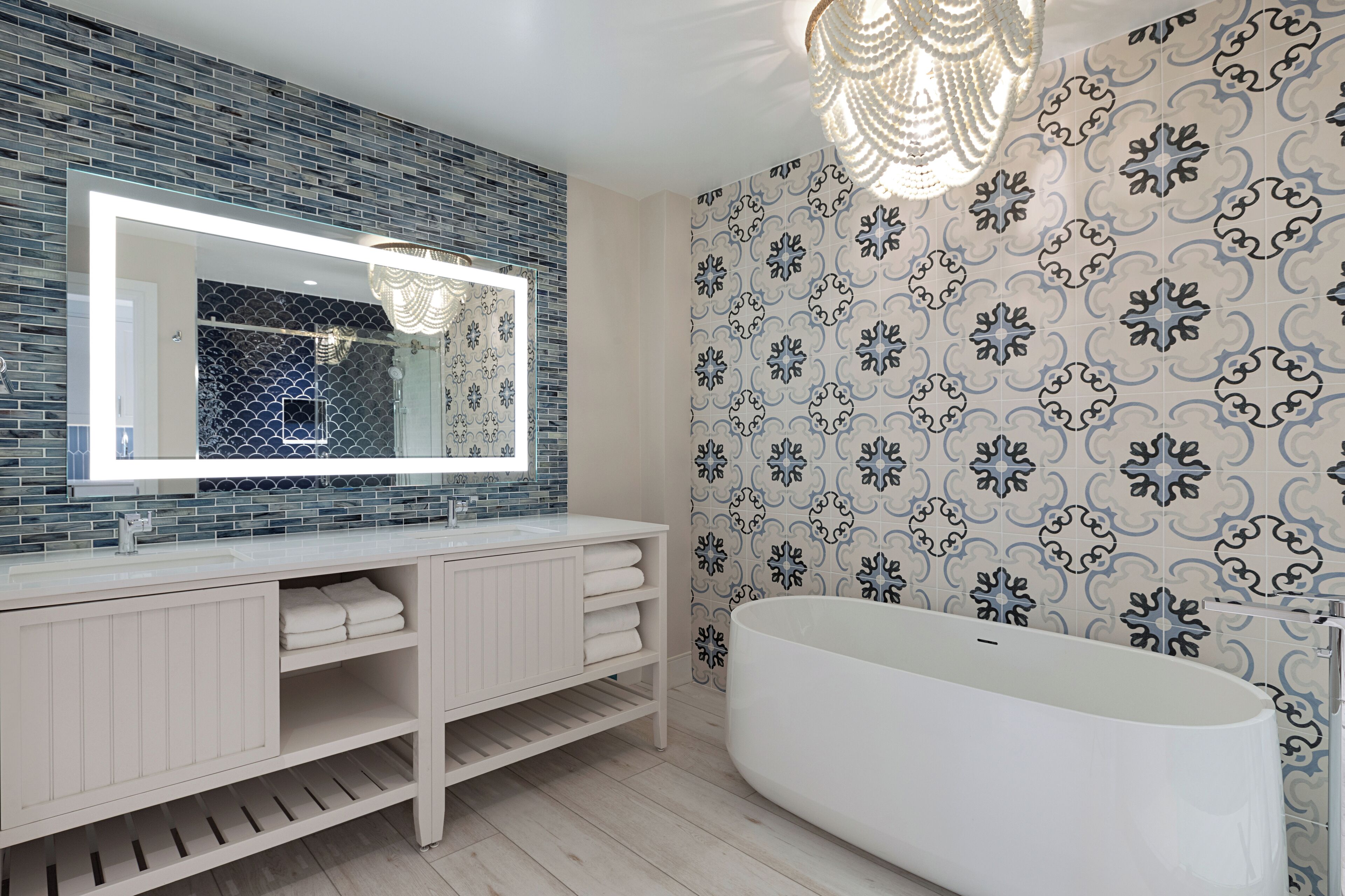 A modern bathroom with a large mirror, white vanity, and a freestanding bathtub.