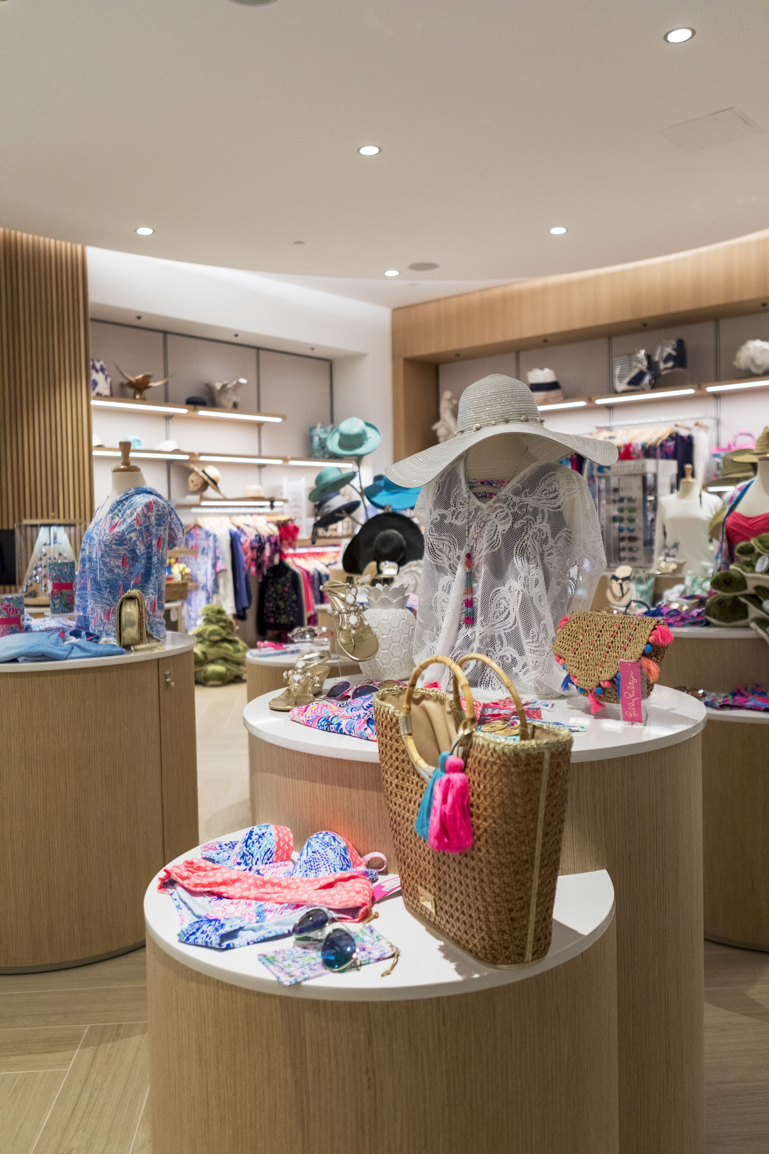 A modern boutique with round display tables showcasing handbags, hats, and accessories.