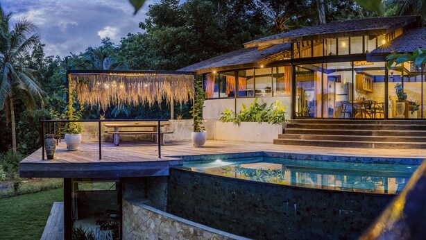 A modern house with a pool, large windows, and a covered outdoor area.