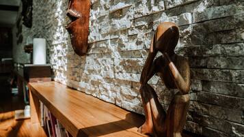 A wooden bench with books, a brick wall, and a wooden sculpture.