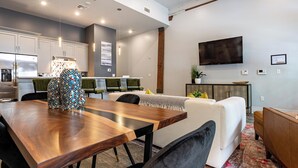 A modern kitchen with white cabinets, a stainless steel refrigerator, and a dining area with a wooden table and chairs. - Luxury Condo Walk Anywhere & Everywhere! The Bordeaux (New Orleans)