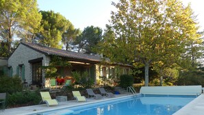 A stone building with a pool and lounge chairs.