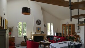 A spacious living room with a fireplace, red furniture, and a dining area with a table and chairs.
