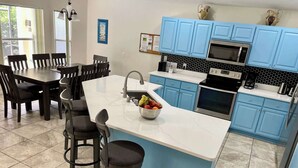 Une cuisine moderne avec des meubles bleus, un plan de travail blanc et un îlot central doté de tabourets de bar.