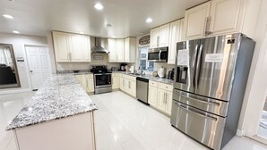 Una cocina moderna con electrodomésticos de acero inoxidable, armarios blancos y encimeras de granito.