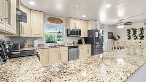 Una cocina moderna con encimeras de granito, electrodomésticos de acero inoxidable y armarios de tonos claros.