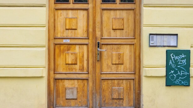 A wooden double door with a metal handle and a small sign above it. - Dalia 3 BR, 2 BA 10 min walk from Old Town Square (Praha 1)