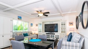 Ein Wohnzimmer mit Fernseher, Sofas, Couchtisch und Deckenventilator.
