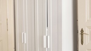 Een witte gesloten deur met een koperen knop en een lichtschakelaar aan de muur.