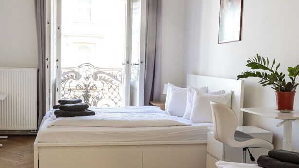 Een hotelkamer met een bed, een stoel, een nachtkastje en een plant in een pot.
