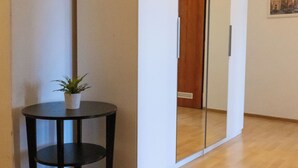 Quarto com porta deslizante, uma mesinha redonda com uma planta e um quadro na parede.