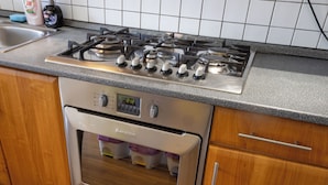 Een keuken met een roestvrijstalen fornuis, oven en houten keukenkastjes.