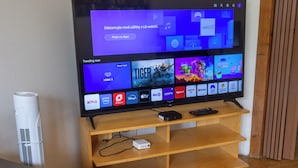 Een flatscreen televisie op een houten standaard, met een afstandsbediening, een stekkerdoos en een kabelontvanger.